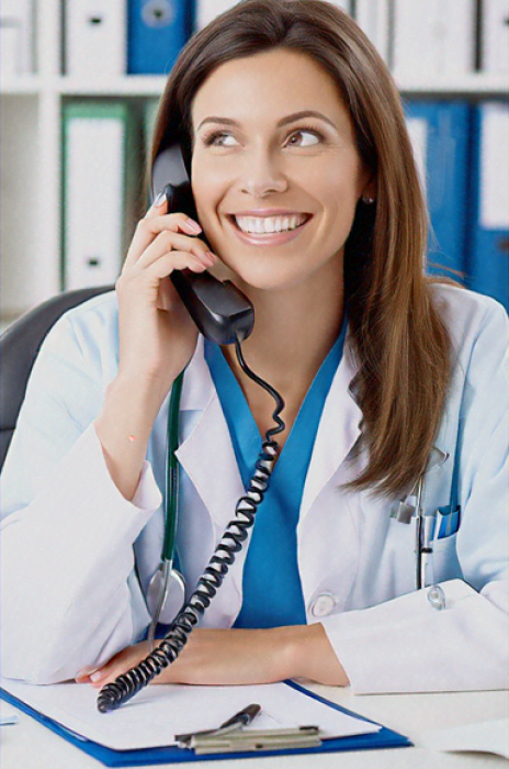 a female doctor sitting at her desk talking on the phone. file on desk. happy face.